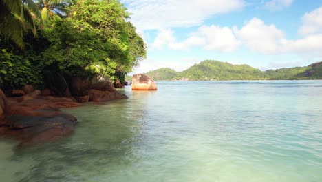 low drone footage near ocean, granite stones and trees near the shore, baie lazare, mahe, seychelles 30fps