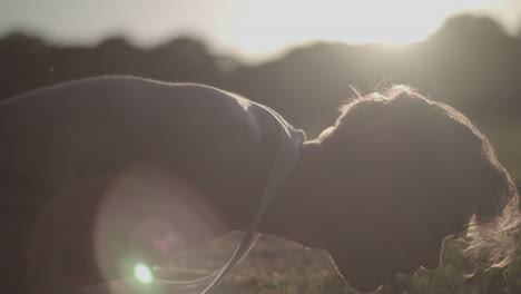 close up shot of young attractive man doing push ups in the park during golden hour - ungraded