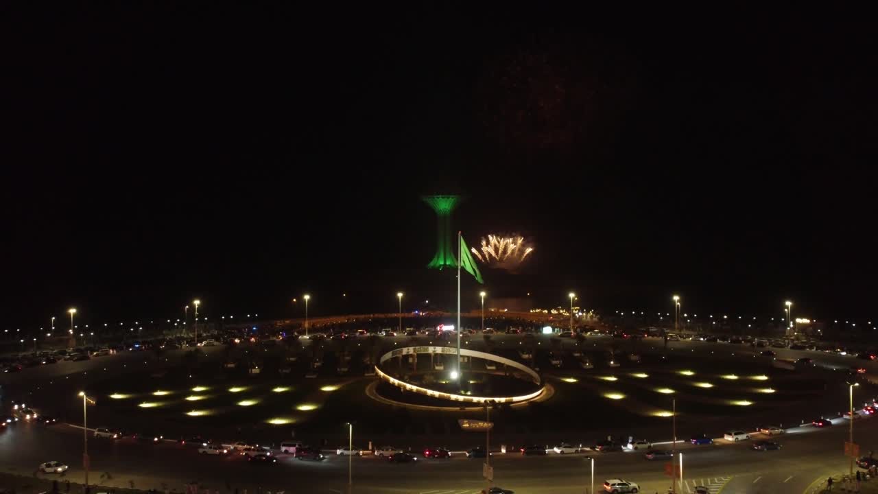 noche con fuegos artificiales, bandera de arabia saudita ondeando, torre khobar en segundo plano