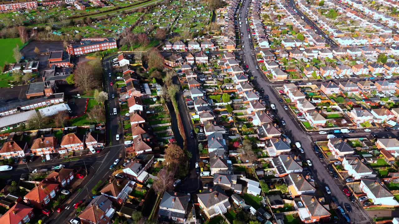 Prise de vue aérienne par drone en plongée sur le lotissement résidentiel de Millbrook à Southampton au coucher du soleil, avec des arbres, des maisons et la nature environnante. Tourné en hiver avec le trafic et les voitures circulant dans les rues.