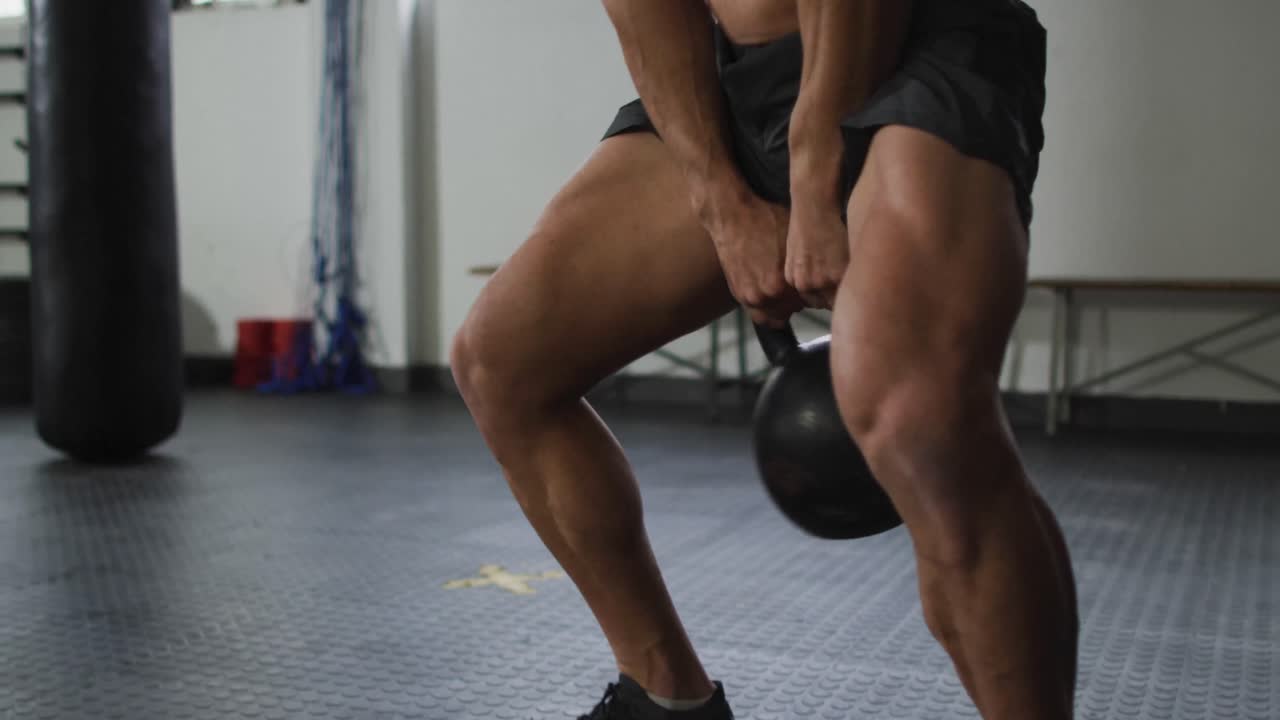 primer plano de un hombre caucásico en forma trabajando con kettle bell en el gimnasio