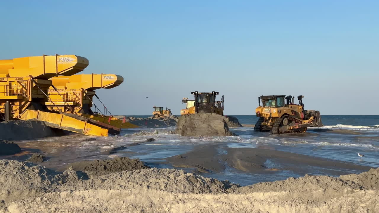 Beach replenishment, sand pump station and bulldozers operating