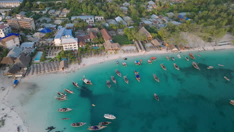 Aerial-view-of-wooden-fisherman-boats-and-sandy-beach-at-Kendwa-village,-Zanzibar,Tanzania-shot-at-30-fps