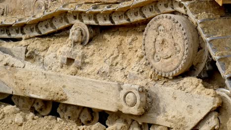 real close up bulldozers tracks sunk into the dirt as it moves backward in construction site