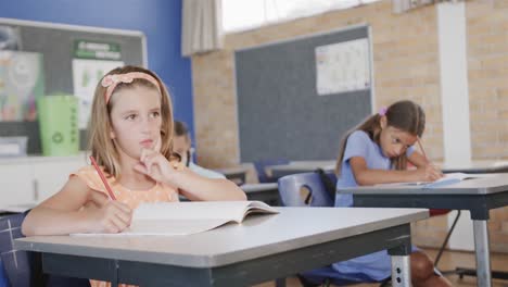 focused, thoughtful diverse schoolgirls working at desks in elementary school class, slow motion