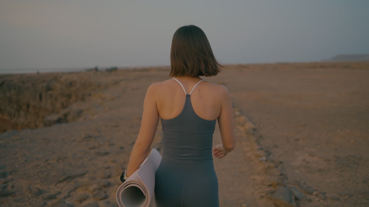 Woman practicing yoga outdoors in the desert at sunset