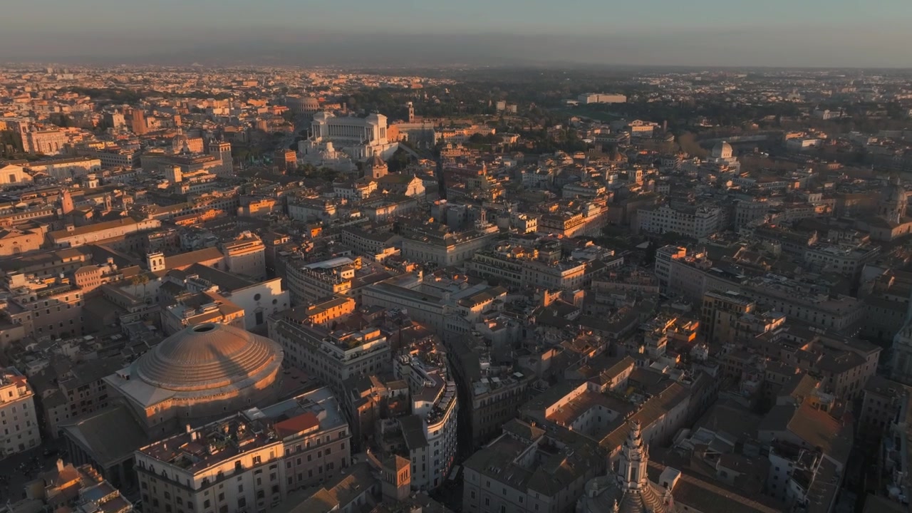 Veduta aerea di Roma, Italia, all'ora d'oro, con famosi tetti storici, cupole e un ampio skyline urbano, con la calda luce della sera che si estende sul centro città e sui monumenti distanti.