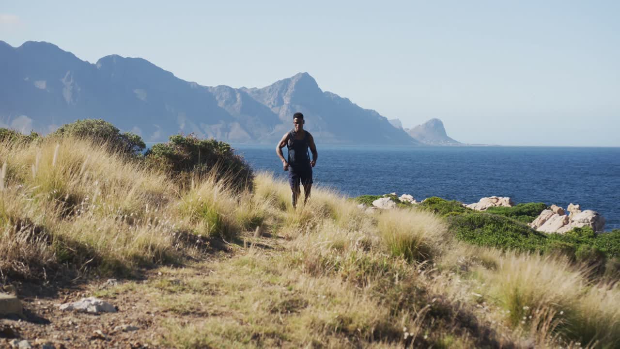 아프리카계 미국인 남자가 야외에서 운동하고 해안가의 시골에서 달리고 있습니다.
