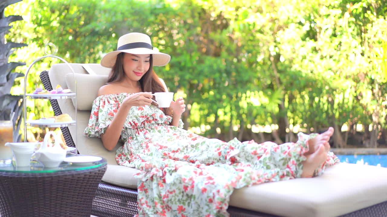 일광욕 라운저 풀사이드에서 휴식을 취하고 있는 예쁜 젊은 여성이 리조트 커피 서비스에서 커피 컵을 선택합니다.