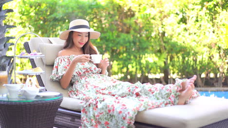 Una-Mujer-Joven-Y-Guapa-Que-Se-Relaja-En-Una-Tumbona-Junto-A-La-Piscina-Selecciona-Su-Taza-De-Café-Del-Servicio-De-Café-Del-Complejo