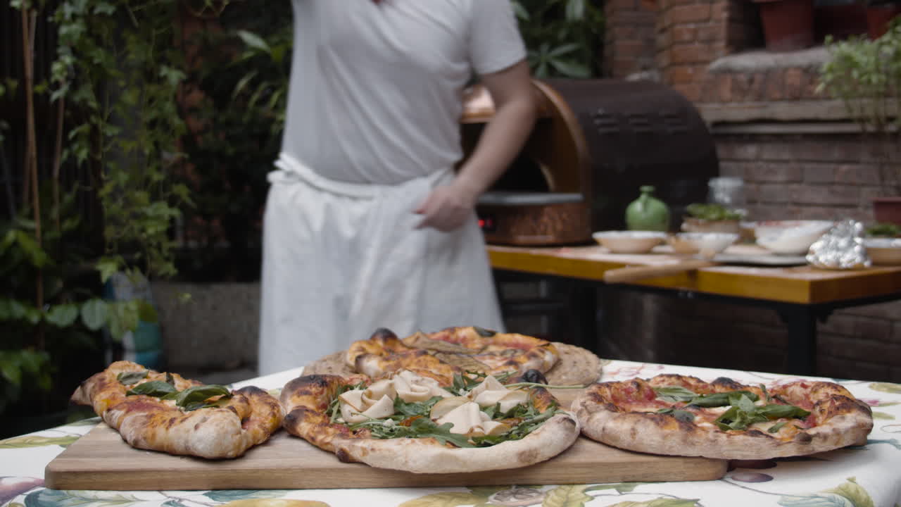 Lo chef mette la pizza appena sfornata dal vassoio sul tavolo.