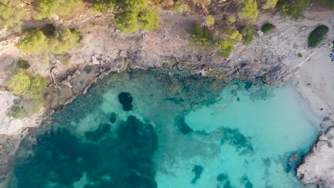 Aerial-top-down-view-of-Mediterranean-beach-near-limestone-cliff,-Mallorca