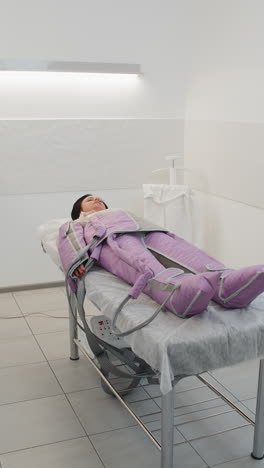 mujer haciendo tratamiento de procedimiento de presoterapia en un salón de belleza acostada en una cama médica y relajándose