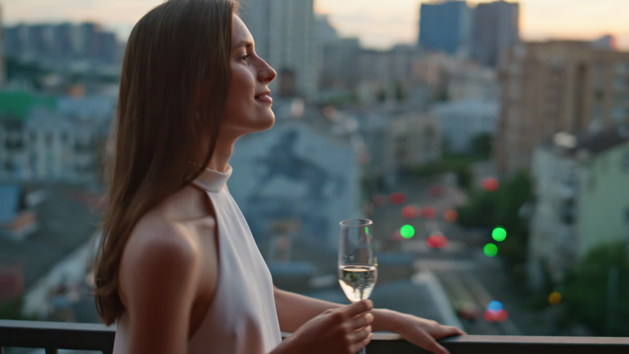 Romantic brunette enjoying evening cityscape standing balcony with glass closeup