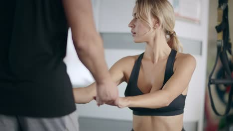 Lächelnde-Fitness-Frau,-Die-Im-Fitnessstudio-Die-Hand-Eines-Personal-Trainers-Hält.