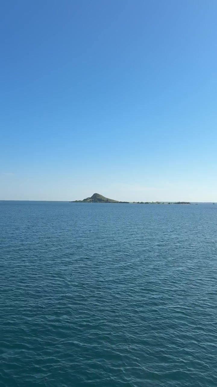 Océano azul en calma con una isla verde distante bajo un cielo despejado