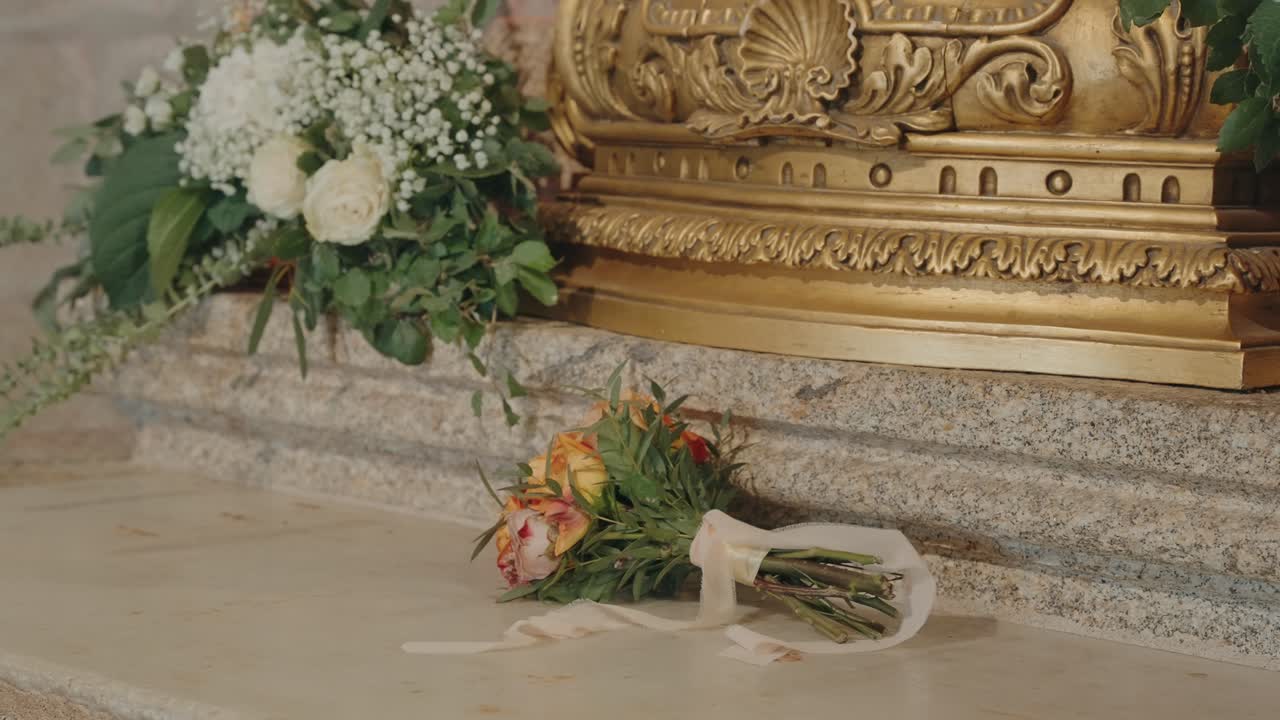 Bouquet da sposa appoggiato su un pavimento di pietra accanto all'altare decorato di una chiesa