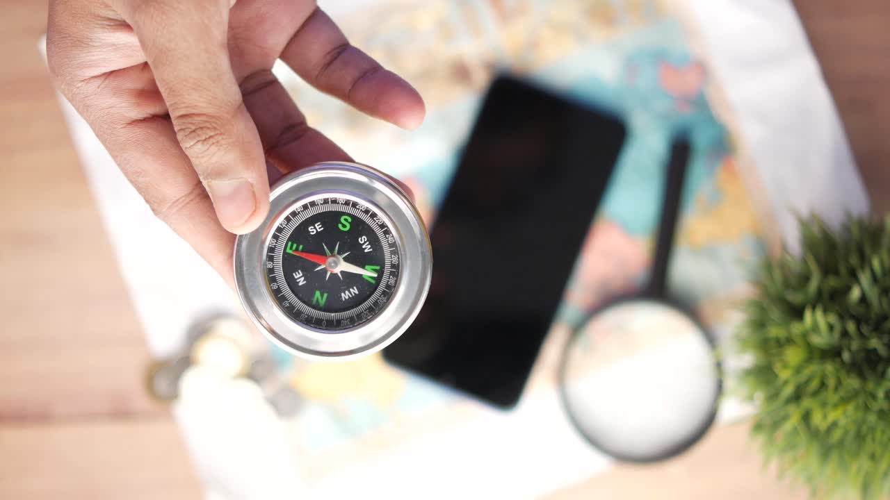 компас, удерживаемый над картой с смартфоном и лупой