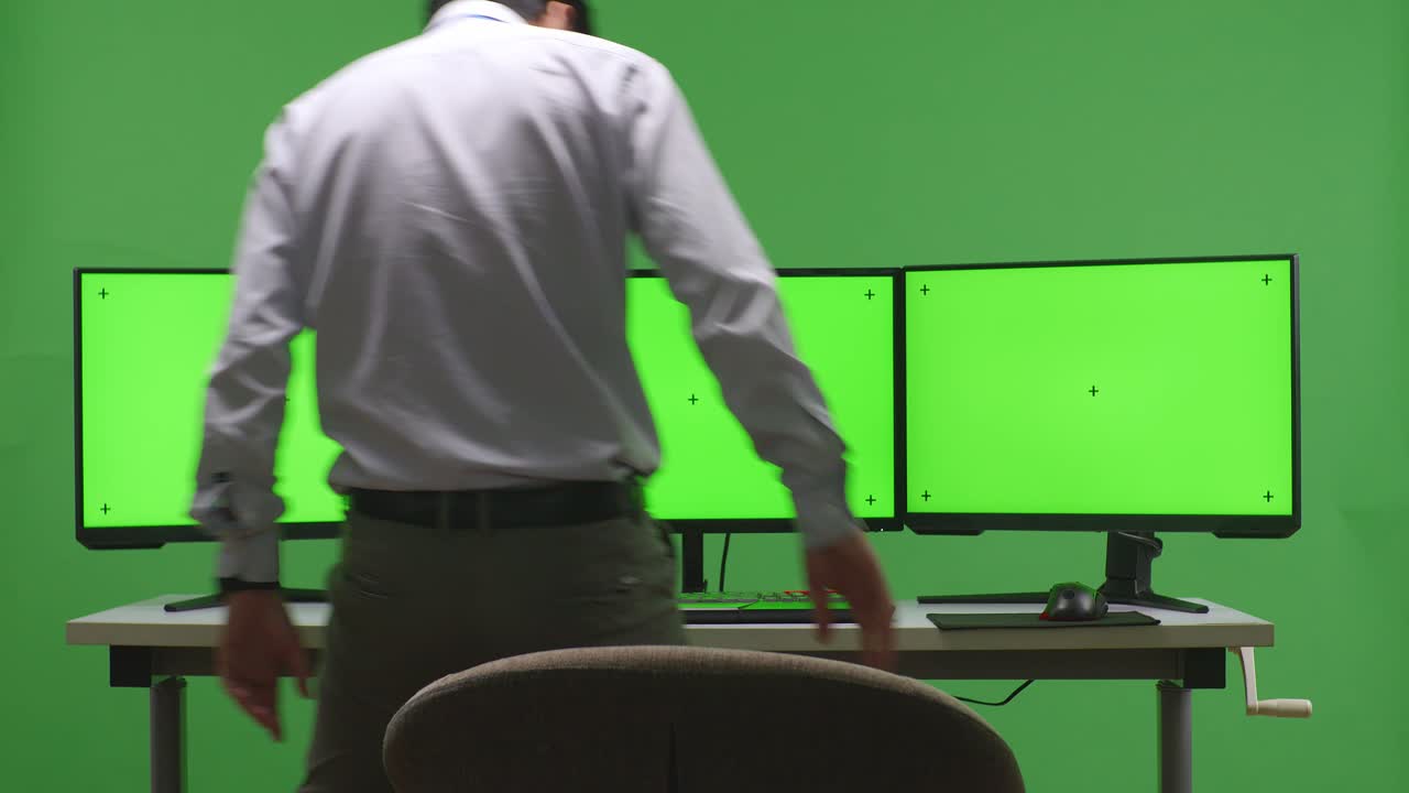 persona que trabaja en un escritorio de varios monitores en una pantalla verde