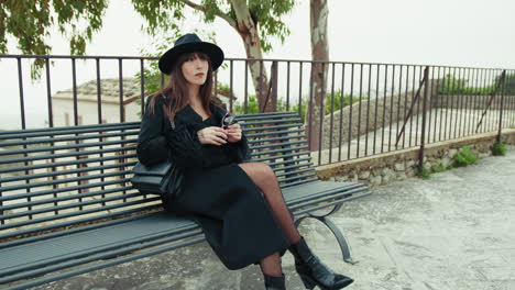 elegant woman relaxing on the park bench holding her sunglasses