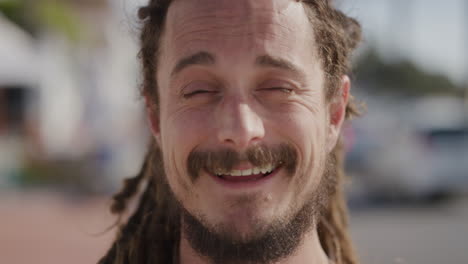 retrato en primer plano de un joven amigable sonriendo alegremente en el fondo de la playa ocupada