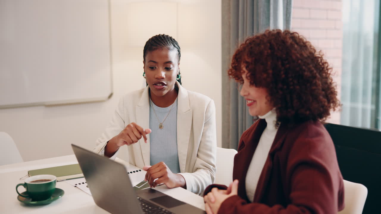 Two businesswomen having a meeting at a desk in an office.