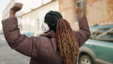 african american woman listening to music walking at street