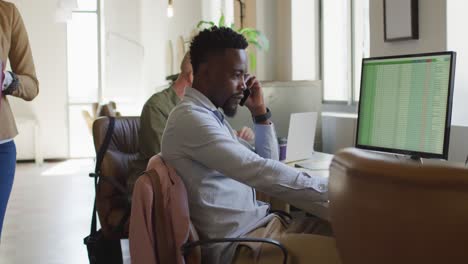 African-american-businessman-talking-on-smartphone-in-creative-office