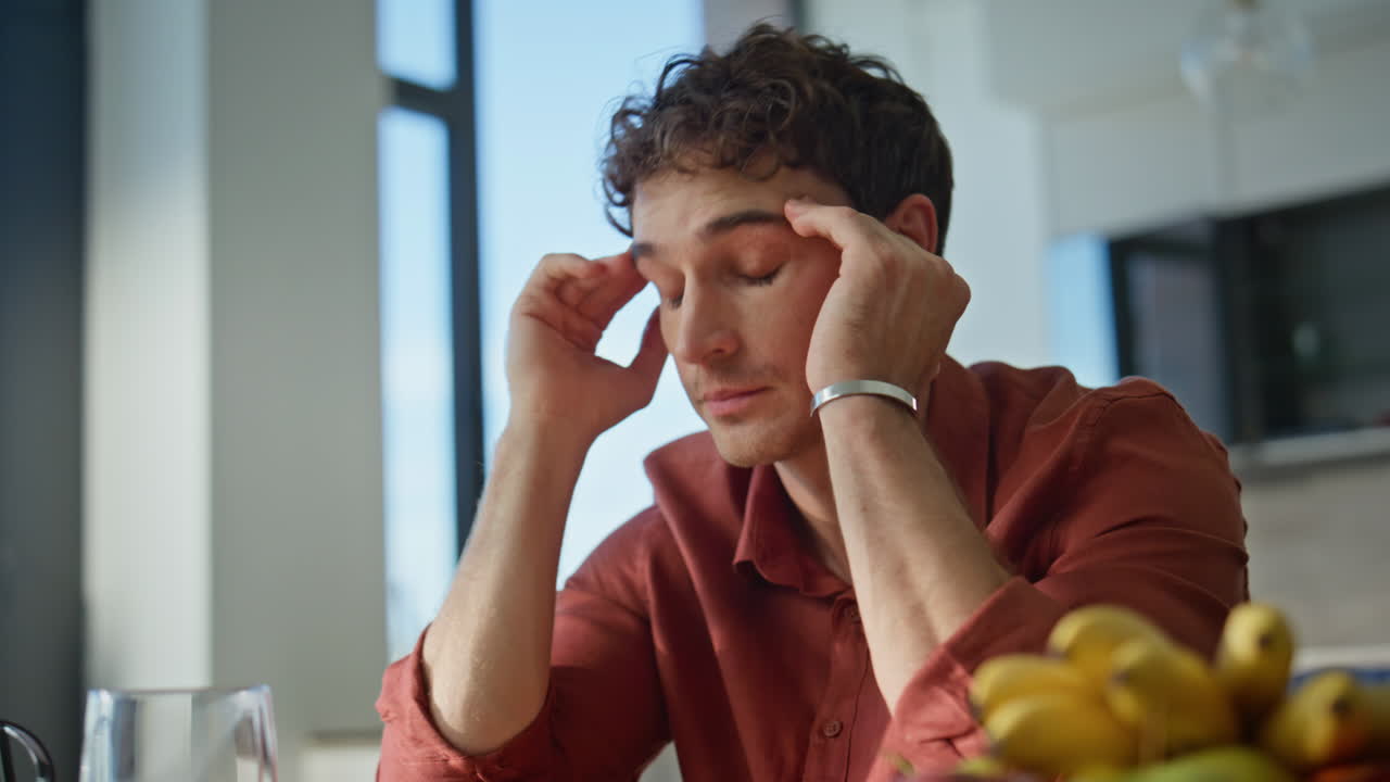 Frustrated man looking cellphone sitting apartment kitchen closeup. Tired guy