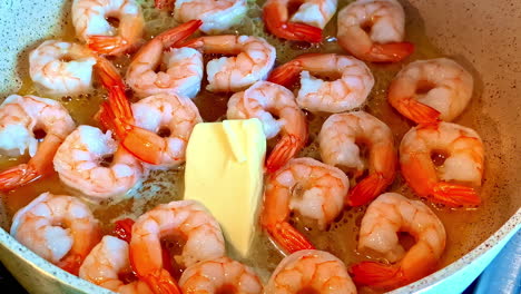 cooking delicious shrimp with butter in hot pan, close up