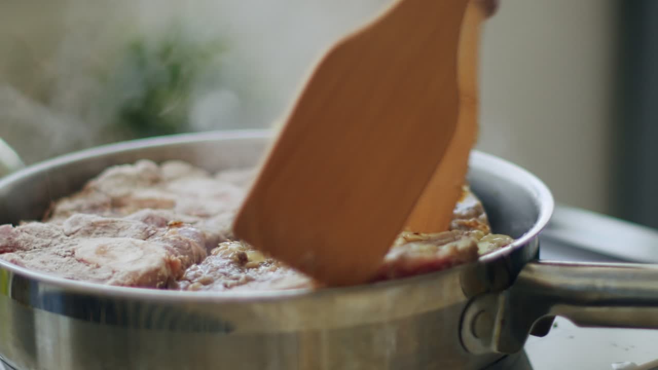 persona que agita los talones de ternera calientes en la sartén