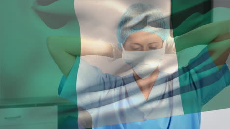 composición digital de la bandera de nigeria ondeando sobre una trabajadora de la salud que lleva una máscara facial en el hospital