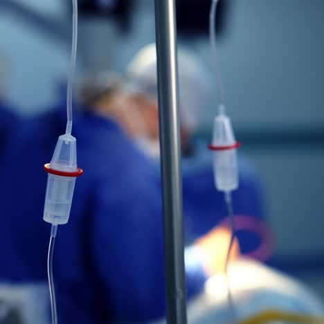 intravenous drip in the operating room. dripper on the background of surgeon's team performing operation