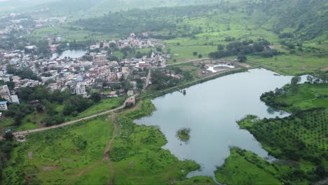 Aerial-view-of-famous-tourist-attraction-Ahilya-Dam-with-the-view-of-Trimbakeshwar-town-during-monsoon,-Nashik,-Maharashtra,-India