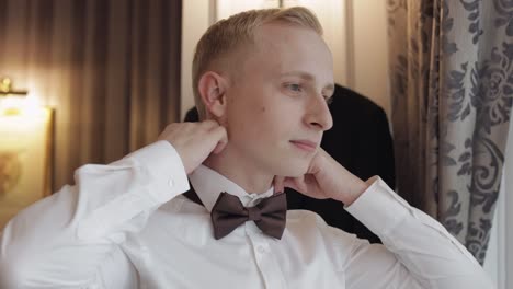 groom man adjusts bow tie, preparing to go to the bride, businessman in white shirt, wedding day