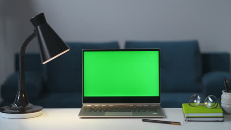 Person-Schaltet-Lampen-Und-Laptop-Im-Zimmer-Aus,-Abends-Mit-Der-Arbeit-Fertig,-Grüner-Bildschirm-Auf-Notebook-Für-Chroma-Key-Technologie,-Nahaufnahme-Auf-Tischoberfläche