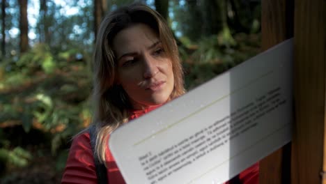 woman reads information sign along a forest trail