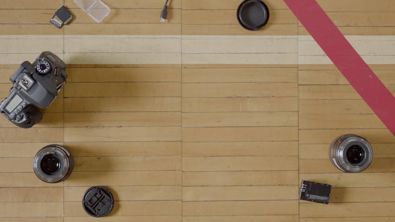 Overhead shot of camera equipment, DSLR equipment, on a wooden basketball court.