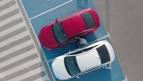 joven conductor discapacitado entrando en un coche rojo de silla de ruedas