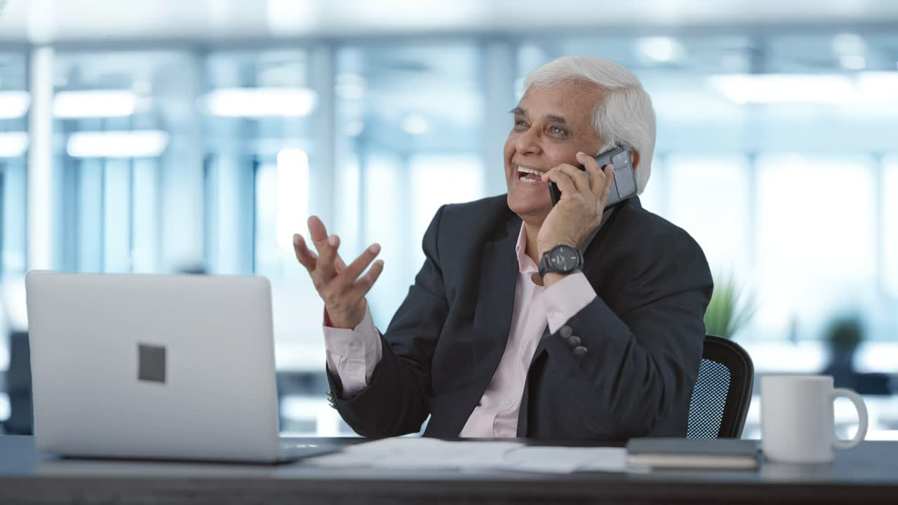 Happy Indian senior manager talking on mobile phone