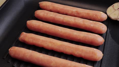 fried sausage on a back grill close-up.cooking corn dogs in boiling pan. traditional asian corndog snacks street food. korean chinese street local market with traditional food. american fast food hot dogs with sauce on the top.