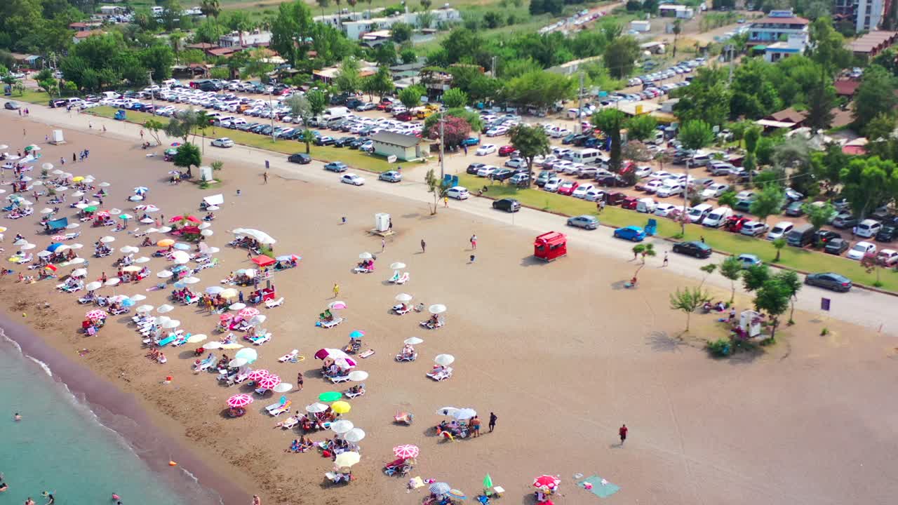 Vista aérea colorida de uma típica praia europeia chamada Adrasan, cheia de pessoas e guarda-sóis em um dia quente de verão ao longo da costa da Turquia