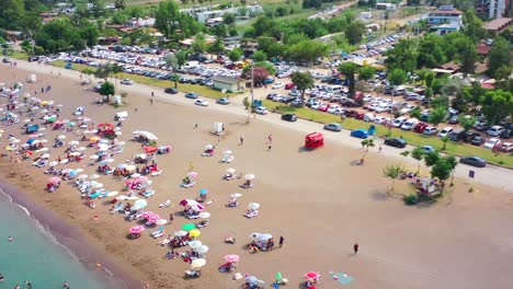 Colorida-Vista-Aérea-De-Una-Típica-Playa-Europea-Llamada-Adrasan-Llena-De-Gente-Y-Sombrillas-En-Un-Caluroso-Día-De-Verano-A-Lo-Largo-De-La-Costa-De-Turquía