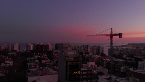 Grúa-De-Construcción-En-La-Ciudad-Al-Atardecer-Toma-Ultra-Ancha-De-Pedestal