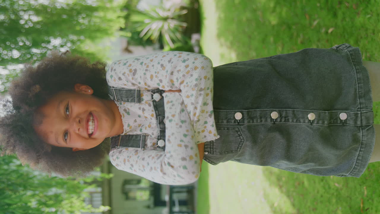 retrato vertical de vídeo de una niña sonriente con actitud de pie en el jardín en casa