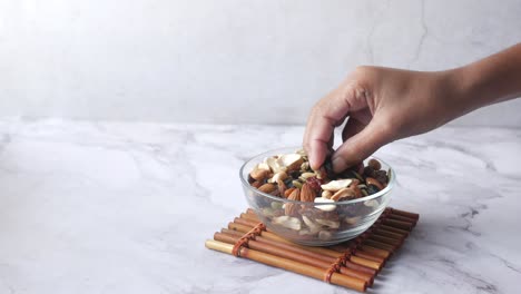 hand picking trail mix from a glass bowl