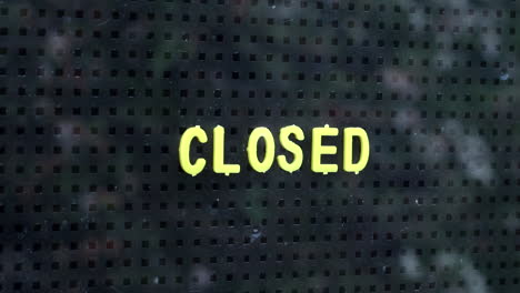 close up of a man placing a closed sign in the window