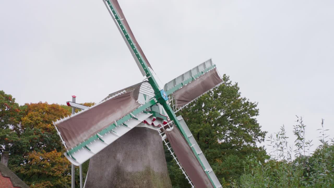 Vista dettagliata delle pale rotanti e della parte superiore dello storico mulino a vento con tetto di paglia presso il Nederlands Openlucht Museum. Il meccanismo mostra l'ingegneria tradizionale ad Arnhem.