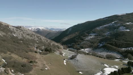 drone view over valsorda, gualdo tadino, on a sunny winter day. snow-dusted peaks rise above a vibrant landscape, blending crisp white and rich earthy tones under a clear blue sky