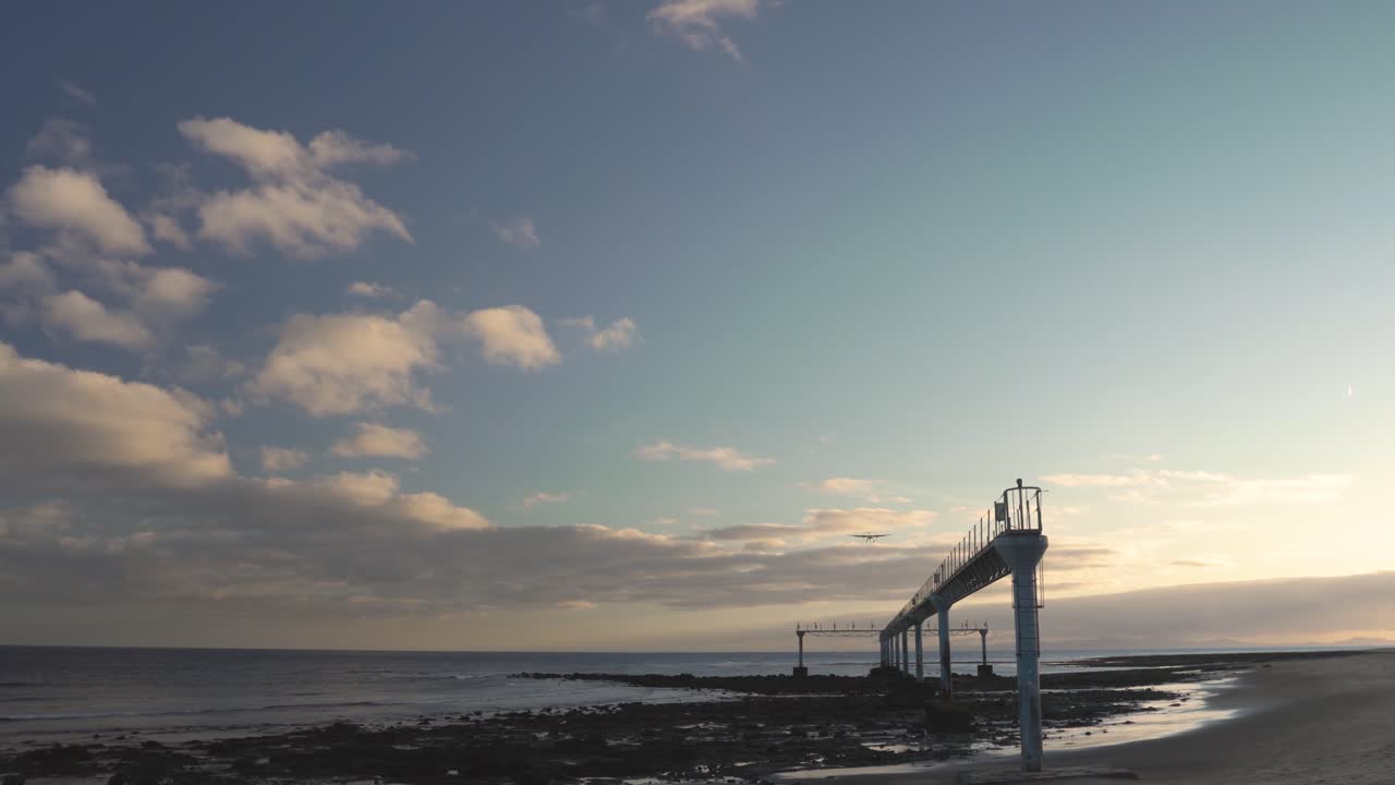 해변에서 해가 지고 비행기가 착륙합니다.